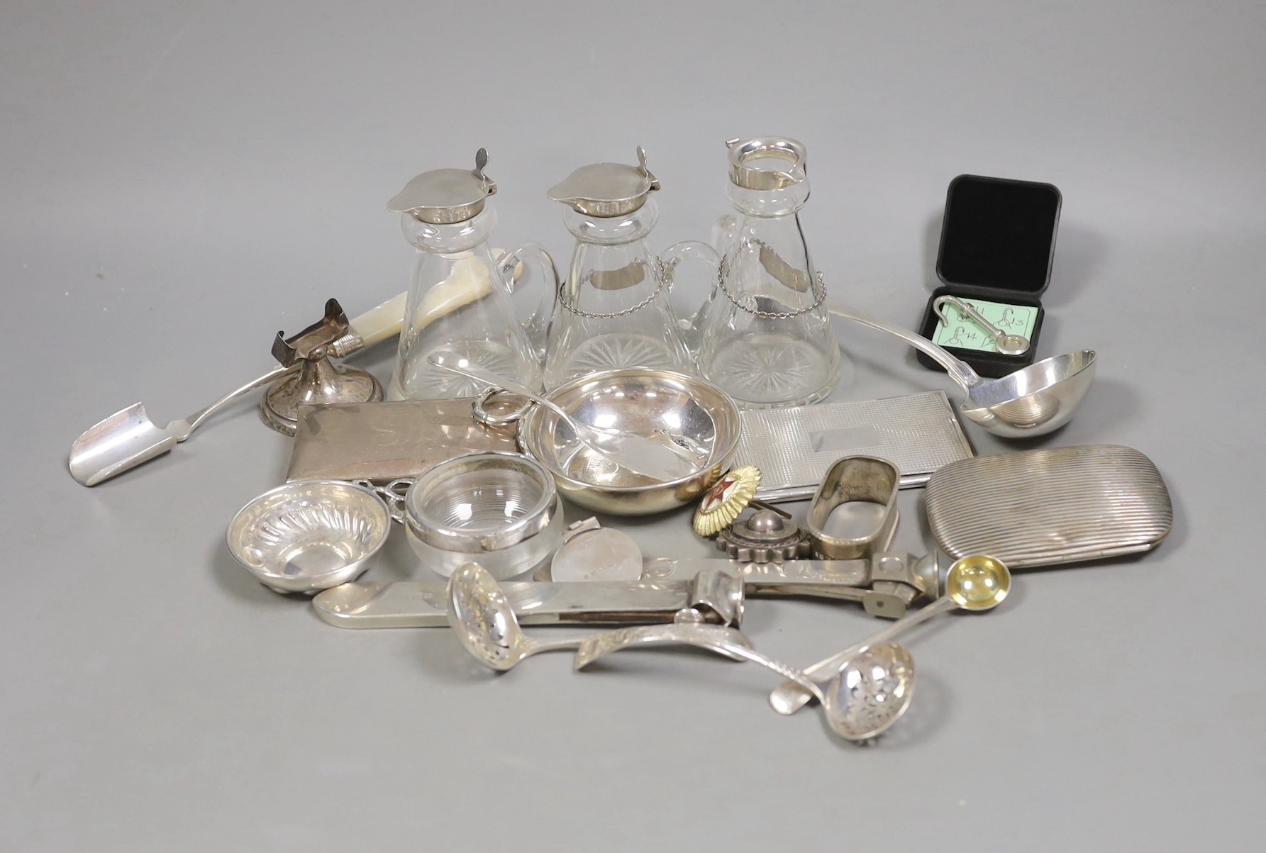 A silver mounted cigar cutter, a similar sterling mounted cutter and a collection of small silver and white metal items including three silver mounted whisky tot jugs including a pair by Asprey & Co, Birmingham, 1913, cu